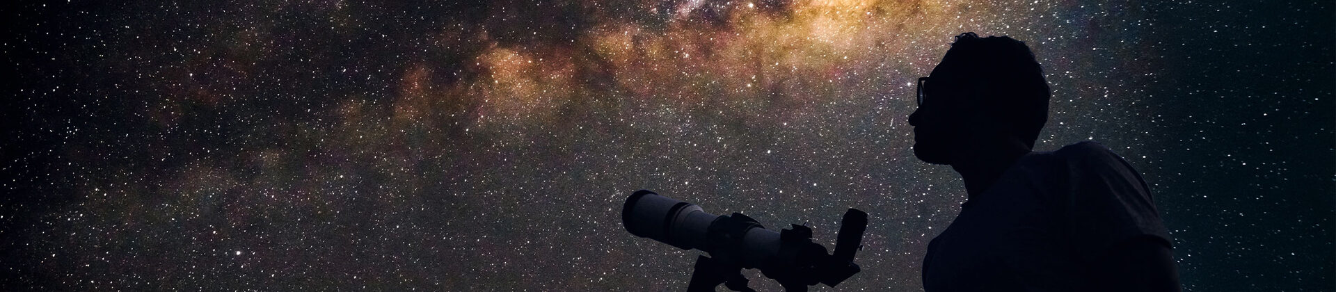 Eine Person schaut mit einem Teleskop in den Sternenhimmel.