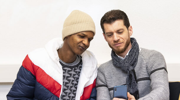 Zwei junge Männer lernen am Smartphone mit der App des vhs-Lernportals