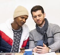 Zwei junge Männer lernen am Smartphone mit der App des vhs-Lernportals