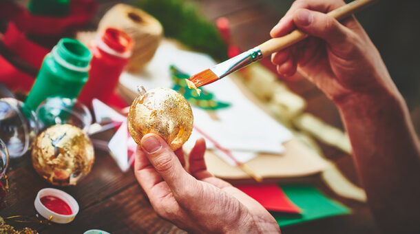 Male hands covering Christmas ornament with gold foil