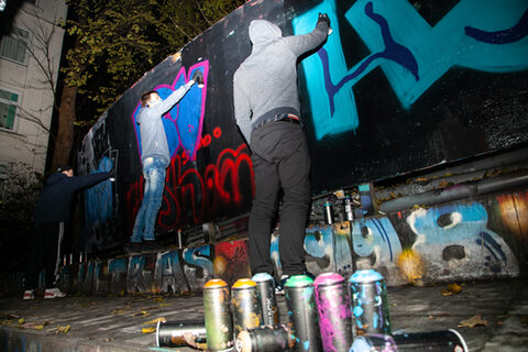 Die Teilnehmer der Hip-Hop-Werkstatt probieren sich beim Sprayen an der Graffiti-Wand aus.