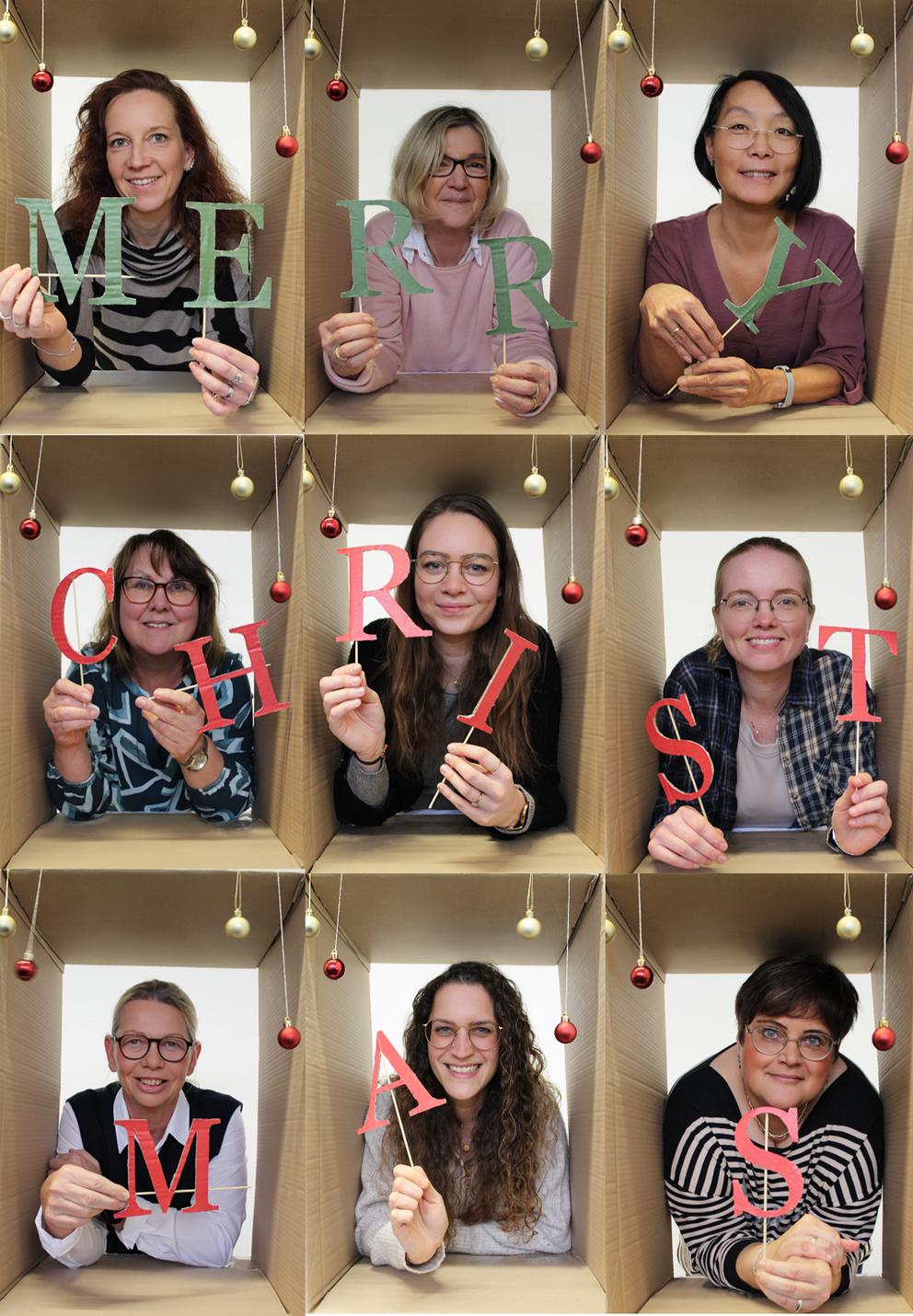 Foto von neun Personen, die jeweils von einem Karton umrahmt werden und die Buchstaben "Merry Christmas" halten.