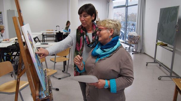 Eine Teilnehmerin und ihre Kursleiterin stehen im Kunst-Atelier der vhs Freiburg vor einer Staffelei