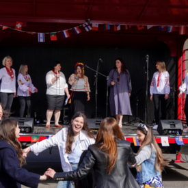 Besucherinnen des Europafestes an der vhs Kleve tanzen vor der Bühne, auf der eine Musikchor singt.