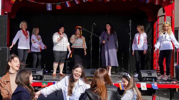 Besucherinnen des Europafestes an der vhs Kleve tanzen vor der Bühne, auf der eine Musikchor singt.