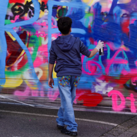 Ein Junge besprüht beim Graffiti-Workshop "Wir gestalten Europa" beim Europafest der vhs Kleve eine Wand.