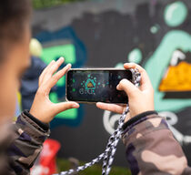 Ein Mädchen macht mit einem Smartphone ein Foto von einem Graffiti an einer Wand