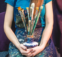 Closeup of female artist hands with paintbrushes